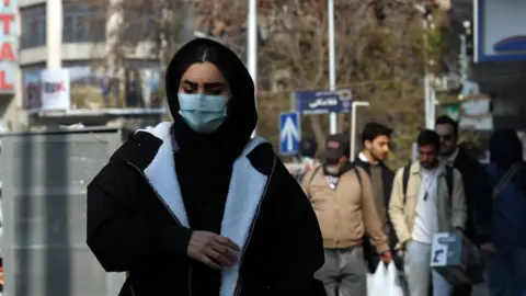 EPA An Iranian woman wearing face mask walks in a street in Tehran, Iran