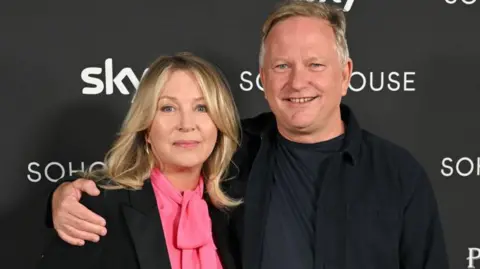 Getty Images Kirsty Young - a woman with blonde hair, wearing a dark jacket and pink top, with Nick Jones, a man with short, light hair and wearing all dark clothing 
