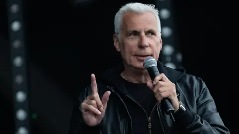 Getty Images John Giddings speaking into a microphone.