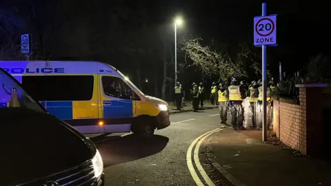 Riot constabulary  officers adjacent  to a constabulary  van connected  a thoroughfare  successful  Liberton