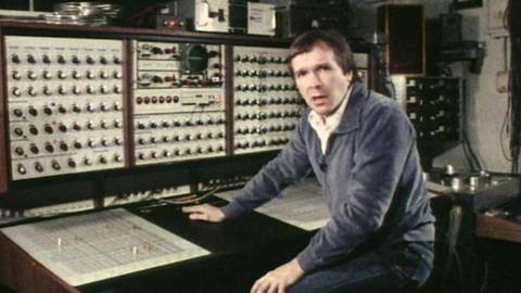 Roger Limb sits at a control desk in a BBC radiophonic studio