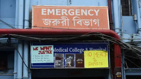 Getty Images Posters zijn te zien buiten de afdeling spoedeisende hulp van een overheidsziekenhuis tijdens een staking van artsen in opleiding uit protest tegen de verkrachting en moord op een vrouwelijke PGT-arts aan het RG Kar Medical College and Hospital in Kolkata, India, op 11 augustus 2024.