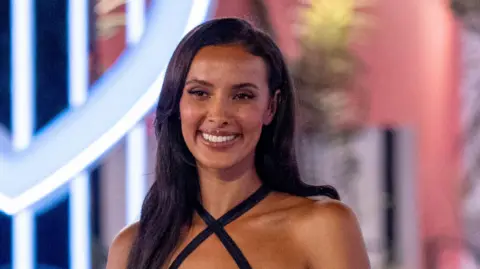 Love Island host Maya Jama wears a black strappy dress.