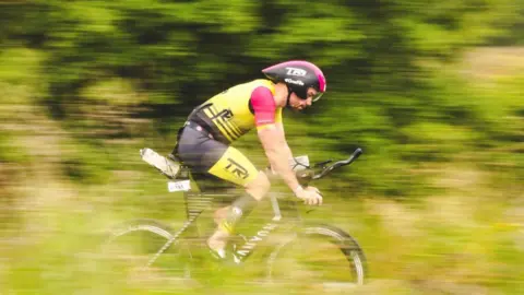 A cyclist speeds through the countryside on a bike.