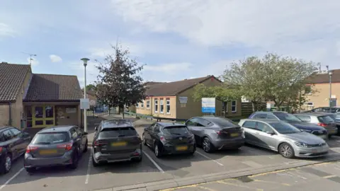 Google Radstock Primary School buildings, with cars parked in front of it as part of a car park.