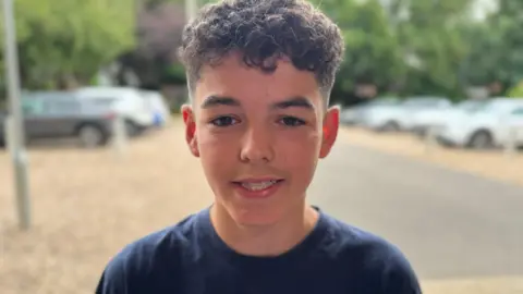 A head and shoulders photograph of 15-year-old Zach. He is wearing a blue T-shirt.