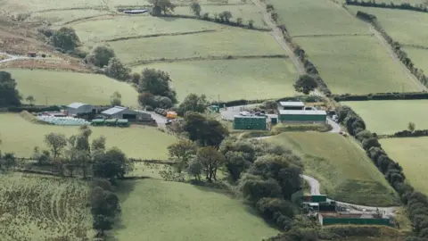 A compound of corrugated iron buildings amid the rolling hills and green fields in the Sperrins area of County Tyrone