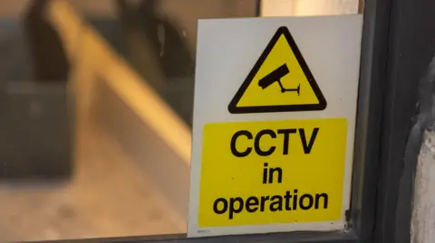 A yellow sign warning of CCTV in operation in a shop