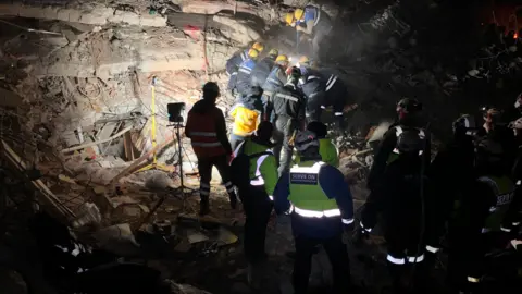 Serve On Volunteers attempting to rescue someone from rubble at night