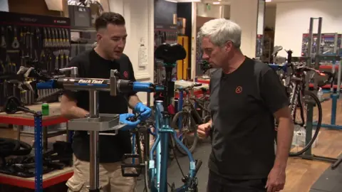 Stephan Jones talks to Darrell while he looks at a bike Darrell has been working on in the Pentonville Prison workshop