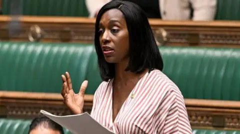 PA Media Florence Eshalomi has medium length straight black hair and is wearing adress with white, maroon and brown stripes