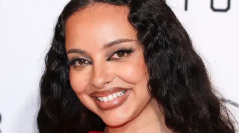 Singer Jade smiles - she has long wavy black hair