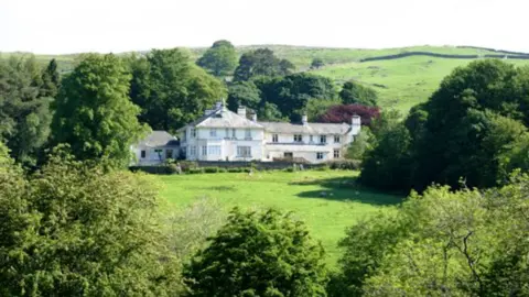 Friends of High Borrans A view of High Borrans, Windermere, an outdoor education centre. The building is large and white with a slate roof and is surrounded by green fields and large trees.