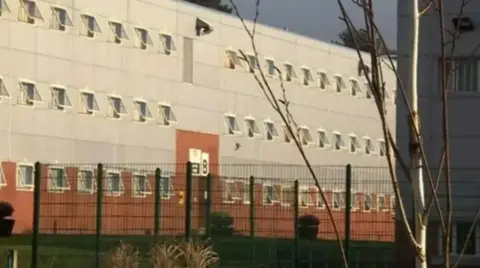 BBC The exterior of Parc Prison in Bridgend, with security fencing surrounding the building.