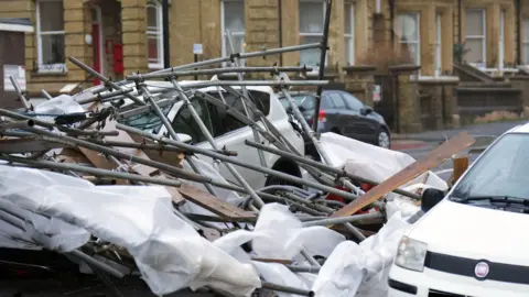 Eddie Mitchell A white car is covered in metal poles. 