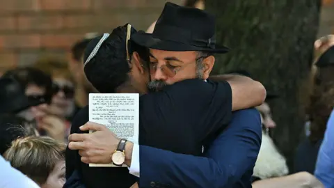 Getty Two men in dark clothing hug