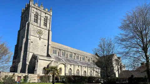 Christchurch Priory is a large stone church - the sky behind it is blue.
