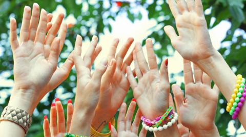 A picture of hands in the air, all wearing colourful bracelets