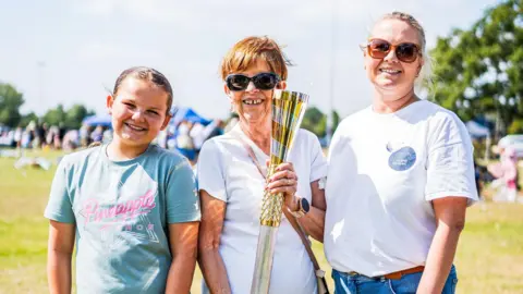 Supplied Claire Goring (right) with her mum Christine (centre) who is holding a golden baton, and daughter Ivy (left)