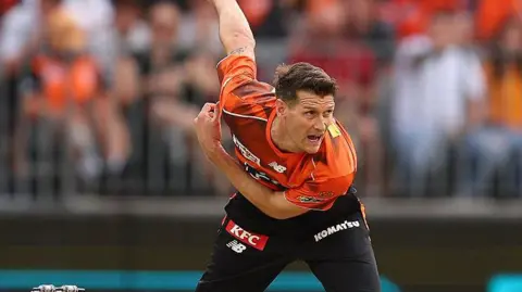 David Payne leans forward after bowling the ball during a match for Perth Scorchers