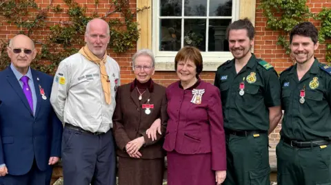 Suffolk County Council A group of two women and four men, including two who are wearing a paramedics uniform and one in Scouts attire. 