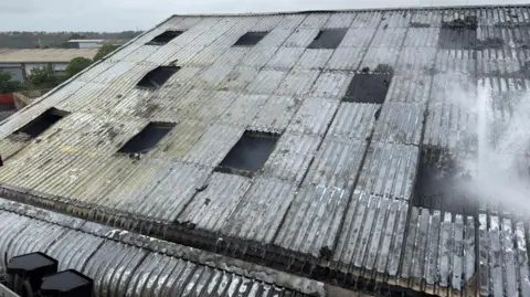 DWFRS The charred metal roof of a building with missing panels.