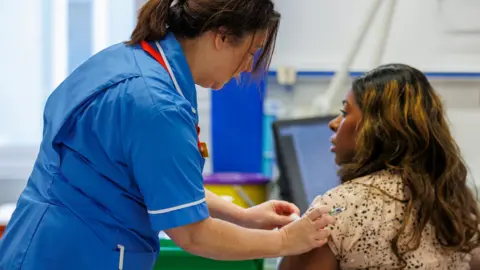 PA Media A healthcare professional administers a flu jab to a patient in the Ulster hospital vaccination centre in Belfast on 4 December.