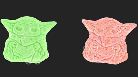 Two green and pink yoda shaped pills - not to scale, on a black background
