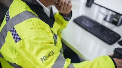 Getty Images Anonymous photo of a police officer looking at a computer at a police station 