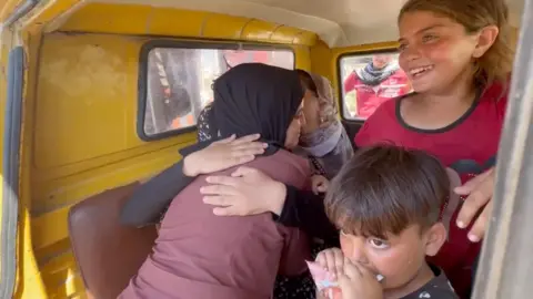 Members of the Al-Fayoumi family hug inside a van on the road south of Gaza City