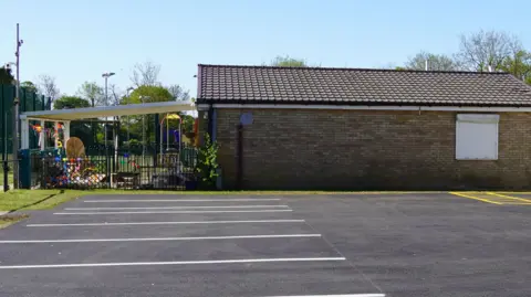 London Luton Airport The new car park at Breachwood Green Village Hall, with markings, that was resurfaced using material from the former runway at London Luton Airport. It is a sunny day. 
