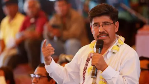 Indigenous lawyer Hugo Aguilar, wearing a white shirt and a flower garland around his neck, delivers a speech during a rally in support of his candidacy as Justice of Mexico's Supreme Court of Justice in San Agustin Tlacotepec, Oaxaca state, Mexico May 28, 2025.