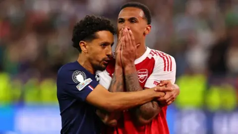 EPA Marquinhos of PSG (L) comforts his countryman Gabriel Magalhaes of Arsenal 
