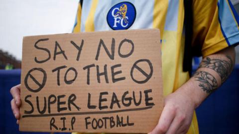 A Chelsea fan holding a protest banner against the European Super League