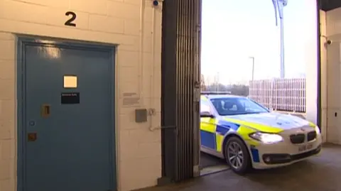 A police car is driving into a garage type door into the police investigation centre. 