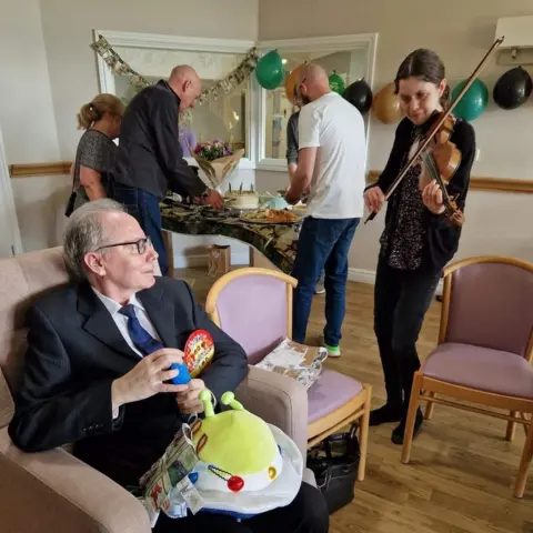 Family Ian Burton watches a violinist at his party