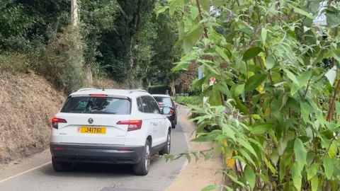 Three cars drive down La Vallee Des Vaux 