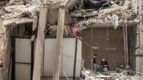 Reuters Two men talk amid the rubble of a destroyed building in Tyre, southern Lebanon (28 April 2026)