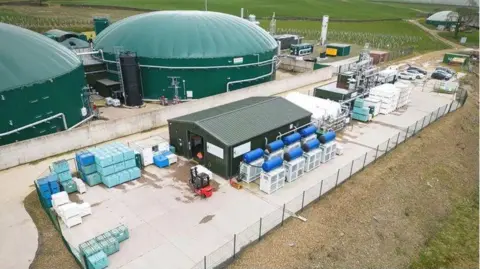 A carbon capture plant with a large green domed roof and various other buildings around it