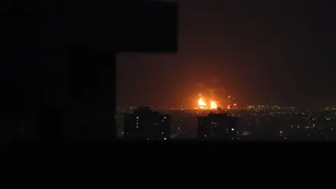 EPA Smoke rises from Tehran's oil refinery after airstrikes in Tehran, Iran, 07 March 2026. The skyline is illuminated by flames rising from the refinery. 