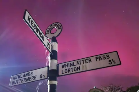 Daphne Eddington Purple skies behind an old-fashioned, black-and-white signpost pointing to Keswick, Buttermere and Whinlatter Pass.