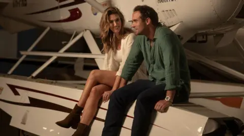 Netflix In a publicity photo for the film Delta Goodrem can be seen sitting on the base of a seaplane alongside her co-star Joshua Sasse