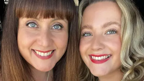 In this picture Jessica (on the right) and her mother Louise (on the left) are smiling in a selfie. Jessica has blonde hair and Louise has brown hair.