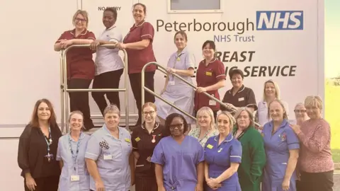 NWAFT A group of nurses wearing different coloured uniforms standing in front of a white mobile screening van