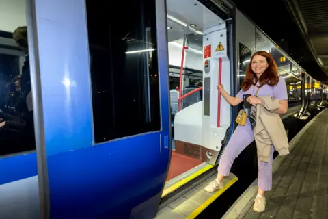 Translink a woman in a purple jumpsuit stepping onto a train