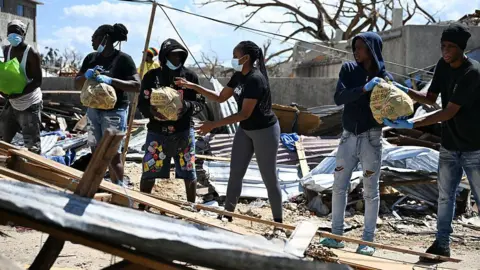 Getty Images Residents help move food supplies at a community center before distribution to the Whitehouse community in Westmoreland, Jamaica
