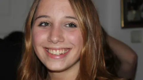 Alice Figueiredo, a young woman with hazel eyes and reddish-brown hair, smiling in a candid photograph.