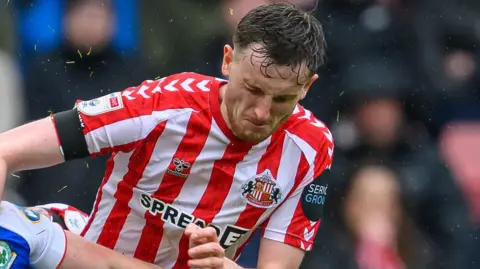 Joe Anderson battling for the ball during a match for Sunderland, with his eyes firmly looking down
