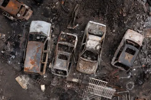 Getty Images Cars destroyed by fire in a yard on July 25, 2022 in Wennington, Greater London