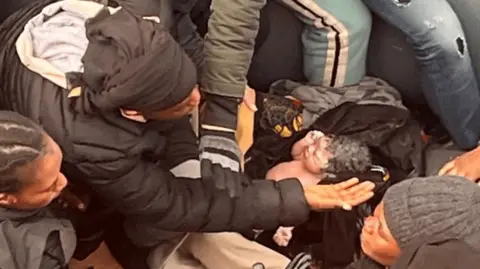 A newborn surrounded by asylum seekers on the dinghy where it was born on January 6, in waters off Spain's Canary Islands